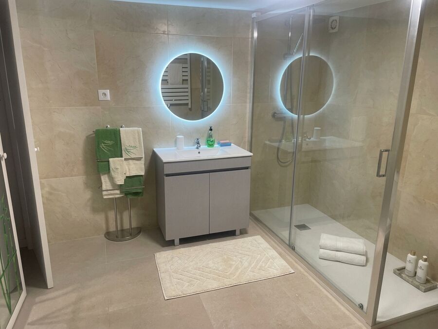 Casa de banho grande renovada com espelhos iluminados e duche no T2 Ofir